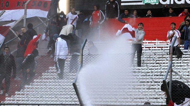 Fanoušky fotbalového týmu River Plate kropí hasiči vodou na stadiónu Monumental. Fanoušky fotbalového týmu River Plate kropí hasiči vodou na stadiónu Monumental.