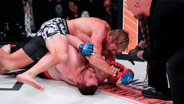 Jake Hager (nahoře) v zápase s T.J. Jonesem. Všemu přihlíží rozhodčí Mike Beltran. Jake Hager (nahoře) v zápase s T.J. Jonesem. Všemu přihlíží rozhodčí Mike Beltran.