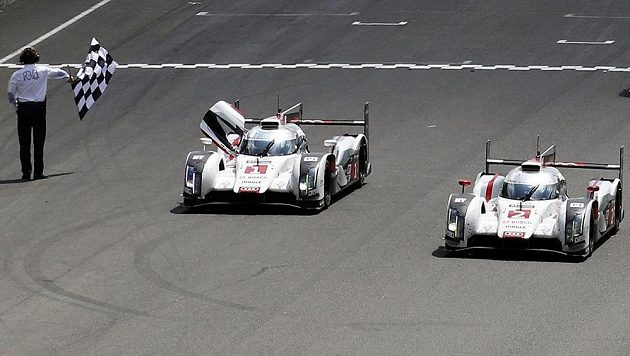 Benoit Treluyer protíná s prototypem Audi R18 e-tron quattro (číslo 2) cíl závodu 24h Le Mans. Vlevo druhé audi pilotované Tomem Kristensenem, který si dojel pro druhé místo. Benoit Treluyer protíná s prototypem Audi R18 e-tron quattro (číslo 2) cíl závodu 24h Le Mans. Vlevo druhé audi pilotované Tomem Kristensenem, který si dojel pro druhé místo.