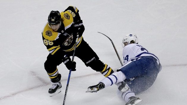 David Pastrňák z Bostonu kontroluje puk před padajícím útočníkem Toronta Kasperi Kapanenem. David Pastrňák z Bostonu kontroluje puk před padajícím útočníkem Toronta Kasperi Kapanenem.
