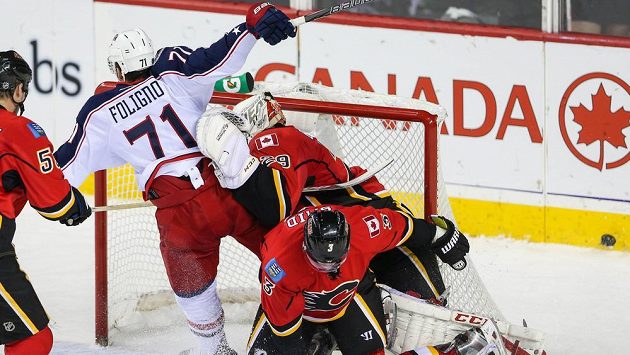 Brankář Calgary Reto Berra (vzadu vpravo) se snaží zabránit ve skórování Nicku Folignovi z Columbusu. Vpravo dole obránce Flames Ladislav Šmíd. Brankář Calgary Reto Berra (vzadu vpravo) se snaží zabránit ve skórování Nicku Folignovi z Columbusu. Vpravo dole obránce Flames Ladislav Šmíd.