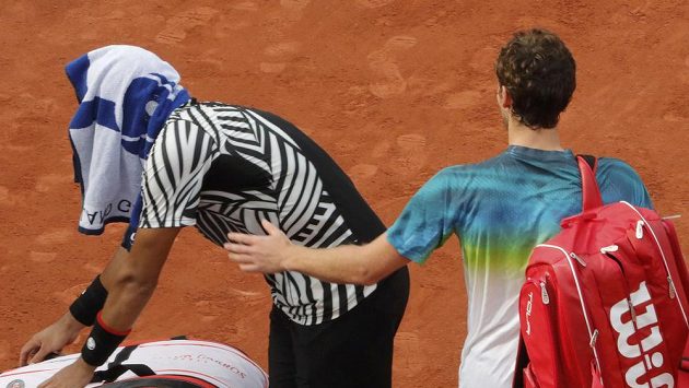 Je konec. Jo-Wilfried Tsonga po skreči zápasu schoval hlavu do ručníku. Kolem něho prochází postupující Ernests Gulbis (vpravo). Je konec. Jo-Wilfried Tsonga po skreči zápasu schoval hlavu do ručníku. Kolem něho prochází postupující Ernests Gulbis (vpravo).