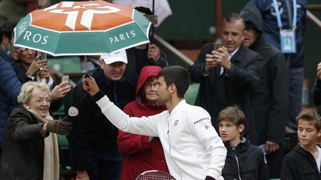 Novak Djokovič si půjčuje deštník od fanynky. Novak Djokovič si půjčuje deštník od fanynky.