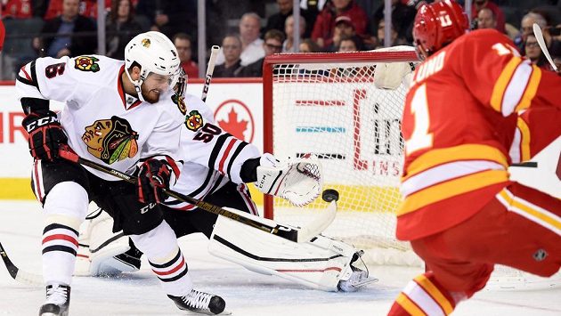 Brankář Chicaga Corey Crawford (50) se vrhá po puku po střele Mickaela Backlunda (11) z Calgary, puk sleduje i obránce Michal Kempný (6). Brankář Chicaga Corey Crawford (50) se vrhá po puku po střele Mickaela Backlunda (11) z Calgary, puk sleduje i obránce Michal Kempný (6).