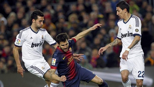 Barcelonský Cesc Fabregas (uprostřed) padá mezi dvojící hráčů Realu Madrid Alvarem Arbeolou (vlevo) a Angelem di Mariou. Barcelonský Cesc Fabregas (uprostřed) padá mezi dvojící hráčů Realu Madrid Alvarem Arbeolou (vlevo) a Angelem di Mariou.