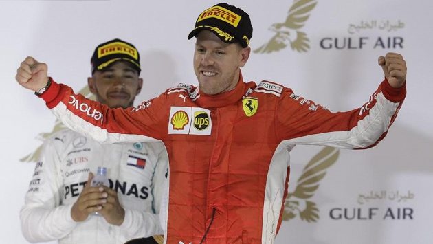 Sebastian Vettel z Ferrari slaví triumf ve Velké ceně Bahrajnu. Za ním stojí úřadující světový šampión Lewis Hamilton. Sebastian Vettel z Ferrari slaví triumf ve Velké ceně Bahrajnu. Za ním stojí úřadující světový šampión Lewis Hamilton.