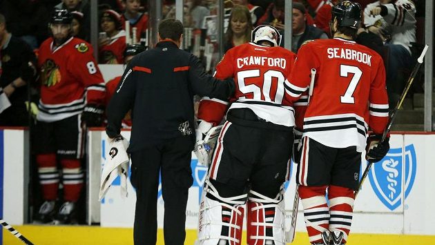 Brankář Chicaga Corey Crawford opouští led za doprovodu lékaře a obránce Brenta Seabrooka. Brankář Chicaga Corey Crawford opouští led za doprovodu lékaře a obránce Brenta Seabrooka.