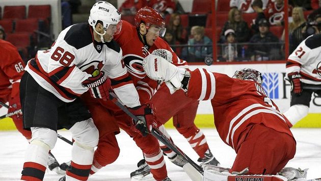 Útočník New Jersey Jaromír Jágr (vlevo) se snaží překonat brankáře Caroliny Cama Warda. Uprostřed je útočník Hurikánů Victor Rask. Útočník New Jersey Jaromír Jágr (vlevo) se snaží překonat brankáře Caroliny Cama Warda. Uprostřed je útočník Hurikánů Victor Rask.