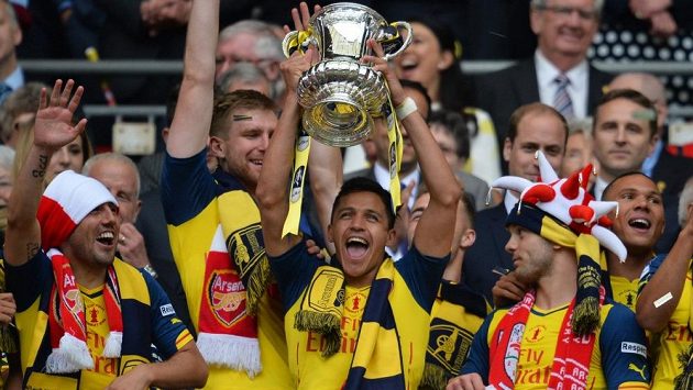 Útočník Arsenalu Alexis Sánchez (uprostřed) s trofejí pro vítěze anglického FA Cupu. Útočník Arsenalu Alexis Sánchez (uprostřed) s trofejí pro vítěze anglického FA Cupu.