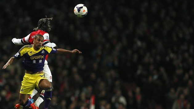 Pravý obránce Arsenalu Sagna vítězí v hlavičkovém souboji proti Routledgeovi ze Swansea (v popředí). Pravý obránce Arsenalu Sagna vítězí v hlavičkovém souboji proti Routledgeovi ze Swansea (v popředí).