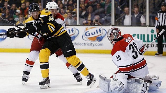 David Krejčí z Bostonu (vlevo) si hledá prostor před brankou Cama Warda z Caroliny. Brání ho Justin Faulk. David Krejčí z Bostonu (vlevo) si hledá prostor před brankou Cama Warda z Caroliny. Brání ho Justin Faulk.