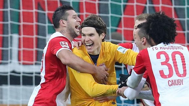 Brankář Marwin Hitz v objetí spoluhráčů z Augsburgu poté, co gólem v nastavení zajistil domácímu týmu remízu v utkání s Leverkusenem. Brankář Marwin Hitz v objetí spoluhráčů z Augsburgu poté, co gólem v nastavení zajistil domácímu týmu remízu v utkání s Leverkusenem.