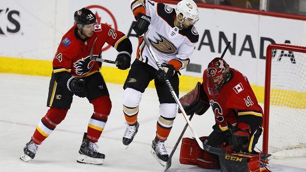 Útočník Anaheimu Andrew Cogliano před brankářem Calgary Mikem Smithem, vlevo zadák Flames Travis Hamonic. Útočník Anaheimu Andrew Cogliano před brankářem Calgary Mikem Smithem, vlevo zadák Flames Travis Hamonic.