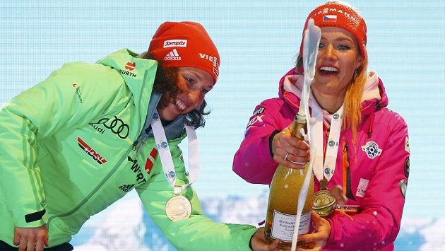 Němka Laura Dahlmeierová (vlevo) pomáhá Gabriele Koukalové při manipulaci se šampaňským na stupních vítězů po nedělní stíhačce. Němka Laura Dahlmeierová (vlevo) pomáhá Gabriele Koukalové při manipulaci se šampaňským na stupních vítězů po nedělní stíhačce.