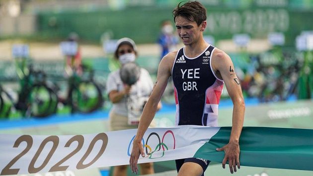 Finišman britské triatlonové štafety Alex Yee probíhá vítězně cílem olympijského závodu. Finišman britské triatlonové štafety Alex Yee probíhá vítězně cílem olympijského závodu.
