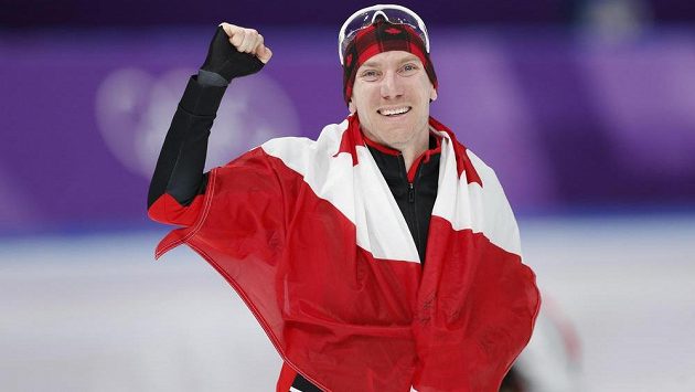 Kanadský rychlobruslař Ted-Jan Bloemen slaví zlatou olympijskou medaili s národní vlajkou. Kanadský rychlobruslař Ted-Jan Bloemen slaví zlatou olympijskou medaili s národní vlajkou.