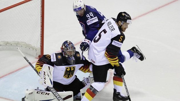 Brankář německé hokejové reprezentace Philipp Grubauer a obránce Korbinian Holzer se snaží zastavit puk mířící na německou branku. Vše sleduje Francouz Tim Bozon. Brankář německé hokejové reprezentace Philipp Grubauer a obránce Korbinian Holzer se snaží zastavit puk mířící na německou branku. Vše sleduje Francouz Tim Bozon.