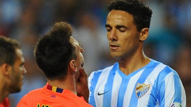 Obránce Málagy Weligton Oliveira drží pod krkem Lionela Messiho. Obránce Málagy Weligton Oliveira drží pod krkem Lionela Messiho.