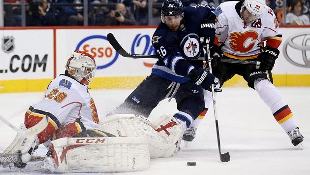Brankář Calgary Flames Reto Berra (29) v jednom z mnoha soubojů s útočníkem Winnipegu Blakem Wheelerem (26). Brankář Calgary Flames Reto Berra (29) v jednom z mnoha soubojů s útočníkem Winnipegu Blakem Wheelerem (26).