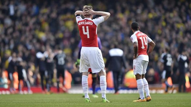 Obránce Arsenalu Per Mertesacker a jeho spoluhráč Theo Walcott sledují radost hráčů Watfordu. Obránce Arsenalu Per Mertesacker a jeho spoluhráč Theo Walcott sledují radost hráčů Watfordu.