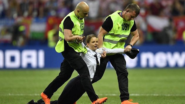 Pořadatelé odtahují ze hřiště ženu, které v průběhu druhého poločasu vnikla spolu s dalšími třemi lidmi na hřiště. Pořadatelé odtahují ze hřiště ženu, které v průběhu druhého poločasu vnikla spolu s dalšími třemi lidmi na hřiště.