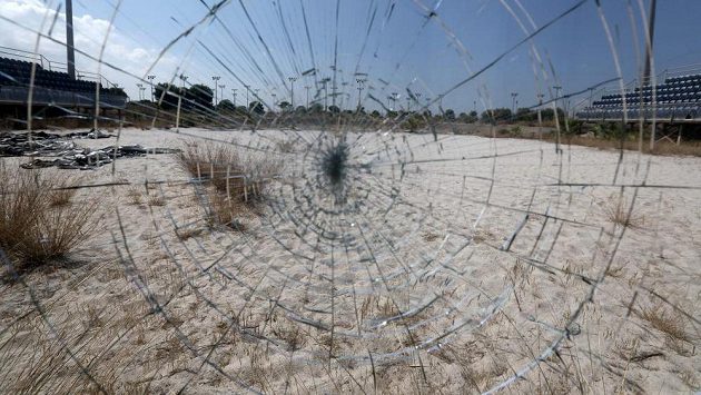 Odraz zpustošeného beachvolejbalového stadiónu v Aténách v rozbitém skle. Odraz zpustošeného beachvolejbalového stadiónu v Aténách v rozbitém skle.