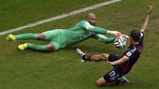 Brankář Tim Howard sbírá míč těsně před kopačkou německého útočníka Thomase Müllera. Brankář Tim Howard sbírá míč těsně před kopačkou německého útočníka Thomase Müllera.