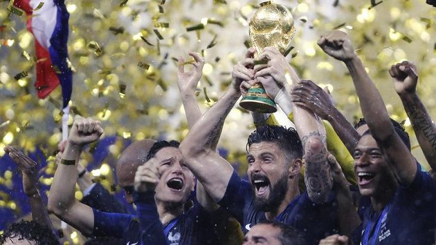 Francouz Olivier Giroud s pohárem v obležení svých spoluhráčů. Francouz Olivier Giroud s pohárem v obležení svých spoluhráčů.