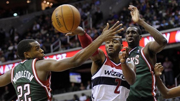 Washingtonský John Wall (uprostřed) posílá přihrávku přes Khrise Middletona z Milwaukee Washingtonský John Wall (uprostřed) posílá přihrávku přes Khrise Middletona z Milwaukee