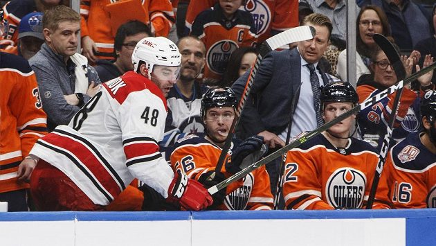 Jordan Martinook (v bílém) z Caroliny skončil po zásahu Zacka Kassiana na střídačce Edmontonu. Jordan Martinook (v bílém) z Caroliny skončil po zásahu Zacka Kassiana na střídačce Edmontonu.