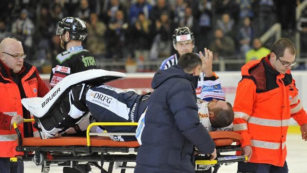 Zraněný brněnský brankář Marek Čiliak zdraví fanoušky, zatímco jej zdravotníci odnášejí z ledu. Zraněný brněnský brankář Marek Čiliak zdraví fanoušky, zatímco jej zdravotníci odnášejí z ledu.