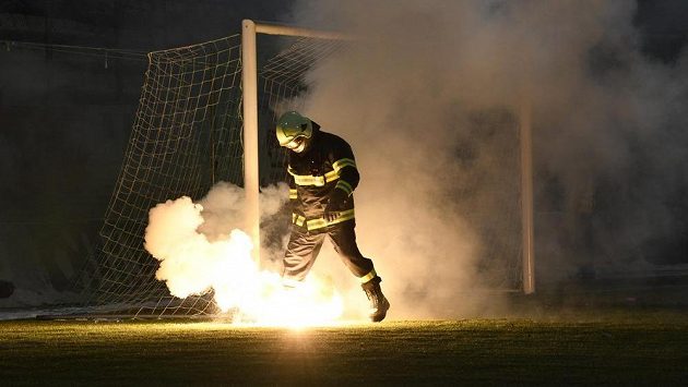 Jeden z hasičů sbírá z hřiště světlice, které tam v úvodu utkání naházeli fanoušci Sparty. Jeden z hasičů sbírá z hřiště světlice, které tam v úvodu utkání naházeli fanoušci Sparty.