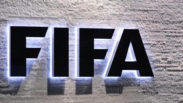 Muž stojící před logem FIFA - ilustrační foto. Muž stojící před logem FIFA - ilustrační foto.