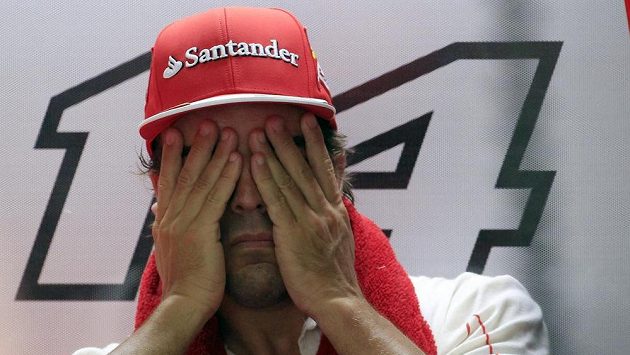 Pilot Ferrari Fernando Alonso stírá pot z obličeje při měřeném tréninku v Sepangu. Pilot Ferrari Fernando Alonso stírá pot z obličeje při měřeném tréninku v Sepangu.