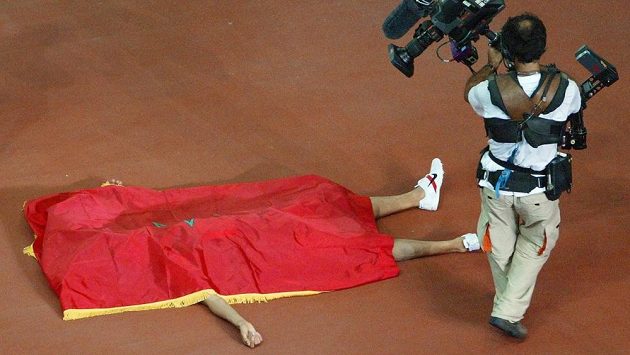 Pod svou národní vlajkou vychutnává Hicham El Guerrouj vítězství na MS v běhu na 1500 metrů roku 2003. Pod svou národní vlajkou vychutnává Hicham El Guerrouj vítězství na MS v běhu na 1500 metrů roku 2003.