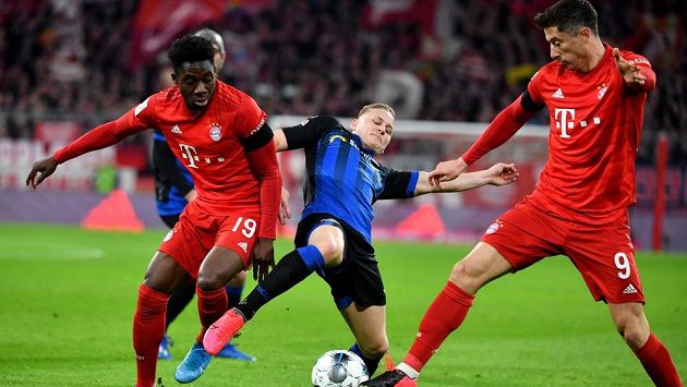 Alphonso Davies (vlevo) a Robert Lewandowski (vpravo) z Bayernu v souboji s paderbornským Kaiem Prögerem. Alphonso Davies (vlevo) a Robert Lewandowski (vpravo) z Bayernu v souboji s paderbornským Kaiem Prögerem.