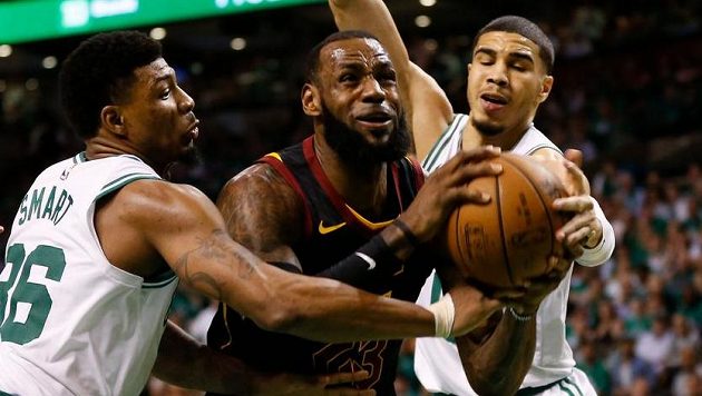 Hvězda Clevelandu LeBron James se probíjí přes dvojici bránících hráčů Bostonu Jaysona Tatuma (vpravo) a Marcuse Smarta. Hvězda Clevelandu LeBron James se probíjí přes dvojici bránících hráčů Bostonu Jaysona Tatuma (vpravo) a Marcuse Smarta.