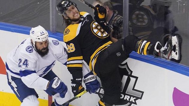 Obránce Tampy Bay Zach Bogosian naráží na mantinel útočníka Bostonu Davida Pastrňáka. Obránce Tampy Bay Zach Bogosian naráží na mantinel útočníka Bostonu Davida Pastrňáka.