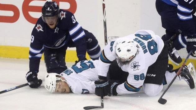 Ke zraněnému Radimu Šimkovi (uprostřed) ze souboje s Andrewem Coppem z Winnipegu (vlevo) se sklání spoluhráč ze San Jose Brent Burns. Ke zraněnému Radimu Šimkovi (uprostřed) ze souboje s Andrewem Coppem z Winnipegu (vlevo) se sklání spoluhráč ze San Jose Brent Burns.