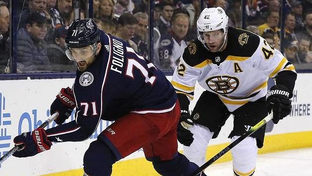 Nick Foligno z Columbusu si kryje puk před Davidem Backesem z Bostonu. Nick Foligno z Columbusu si kryje puk před Davidem Backesem z Bostonu.
